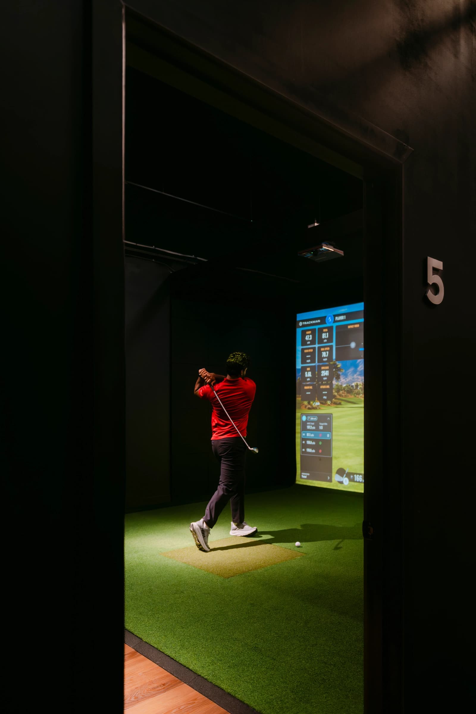 Private indoor golf bay with simulator and seating at Forged Golf